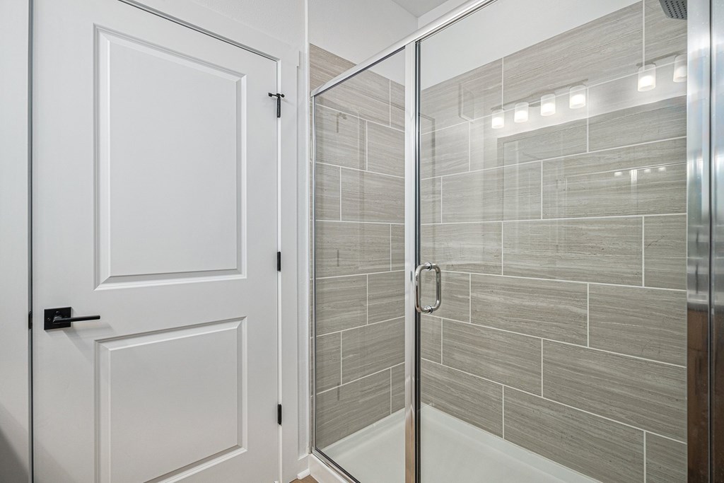 A white door is open to a tiled shower.