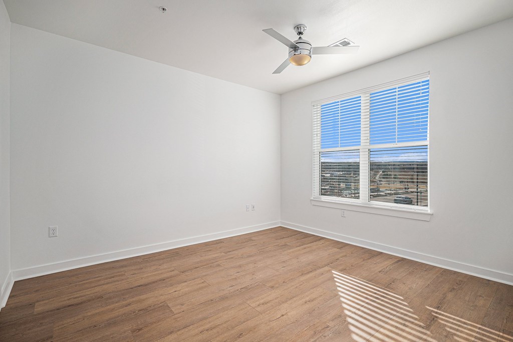 A room with a ceiling fan and a window with blinds.