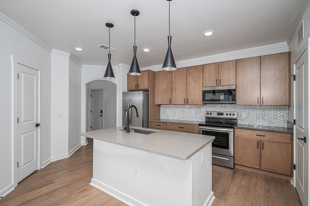 A kitchen with wooden cabinets and a white island.