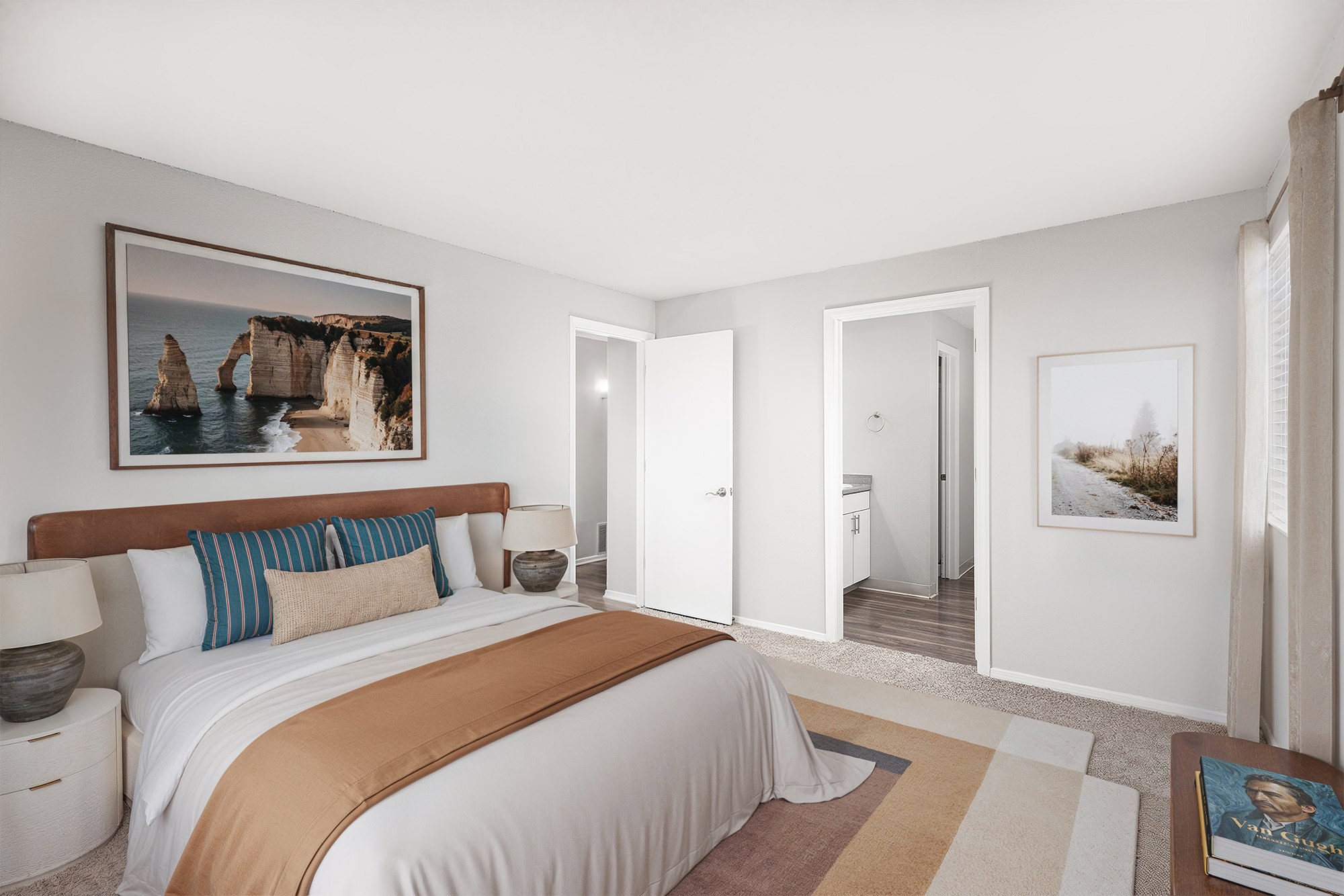 A bedroom with a large bed and a painting on the wall.