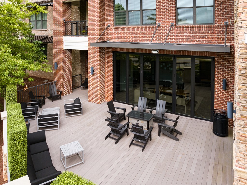 a patio with a table and chairs and a large brick building in the background
