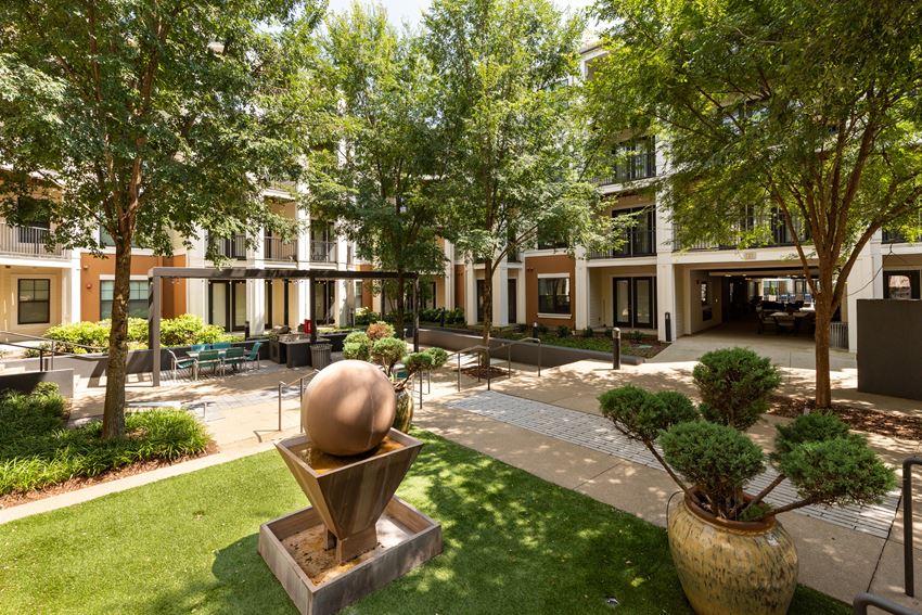a courtyard with trees and a sculpture in front of a building
