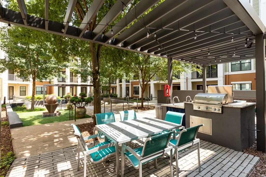 a patio with a table and chairs and a grill