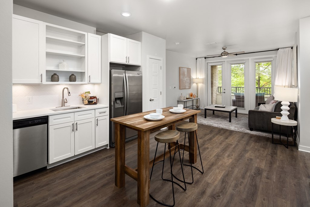 a kitchen with white cabinetry and stainless steel appliances and a wooden island with three stools