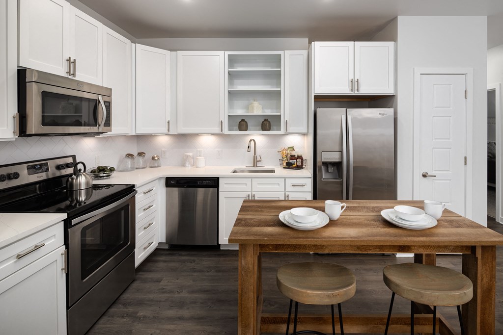 a kitchen with white cabinets and a wooden table