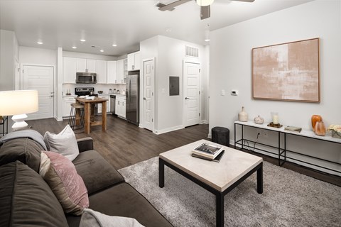 a living room with a couch coffee table and a kitchen in the background