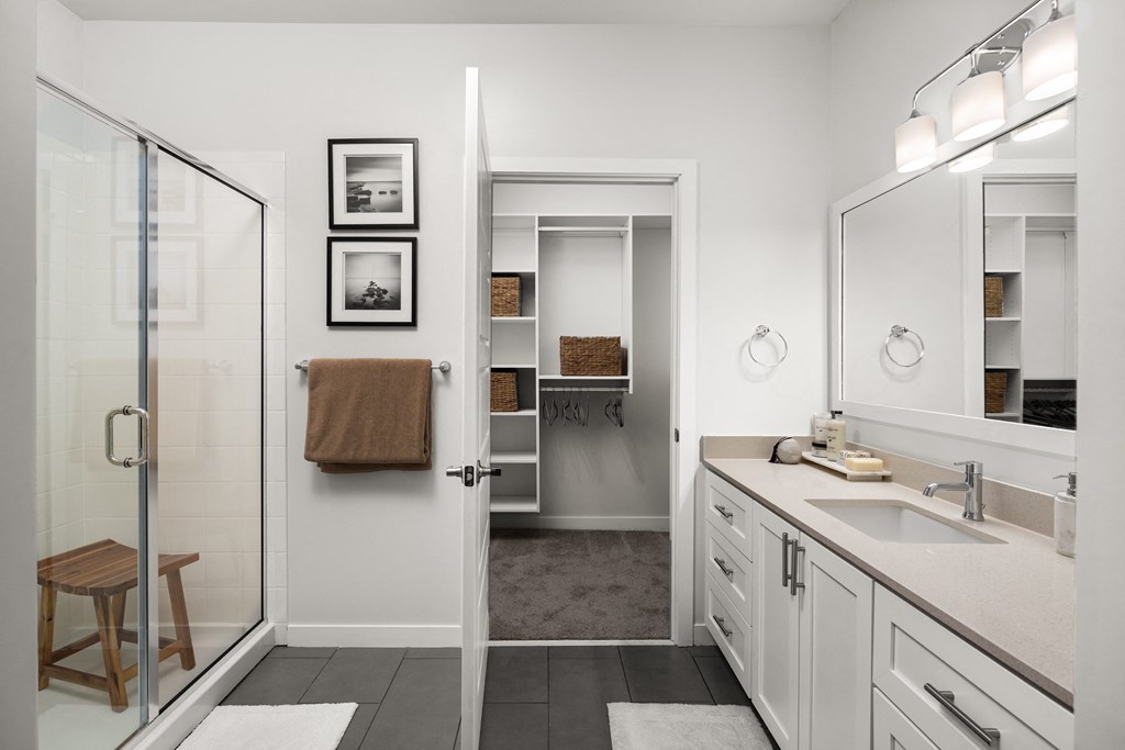 a bathroom with white cabinets and a glass shower door