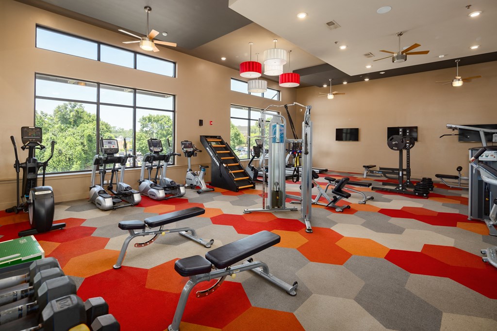 a spacious fitness center with exercise equipment and large windows