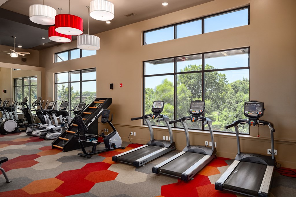 a room filled with cardio equipment and large windows