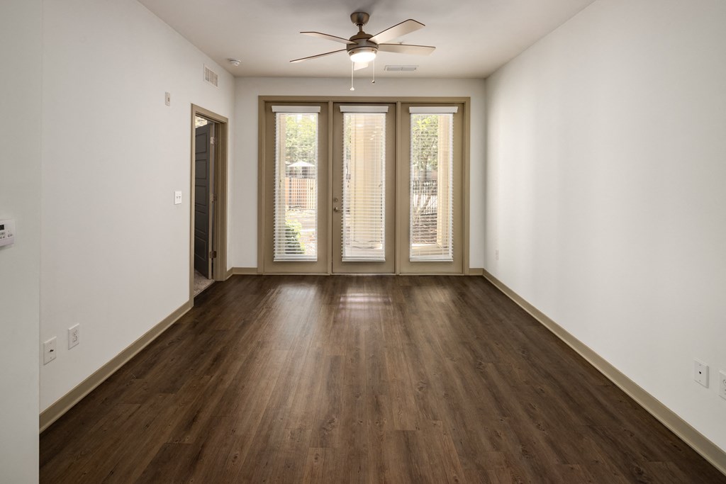 an empty living room with hardwood floors and a ceiling fan
