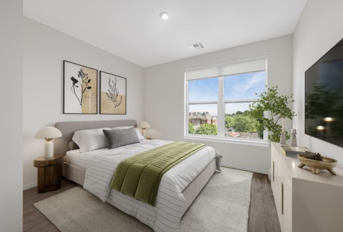 A bedroom with a large bed and a window overlooking a green landscape.