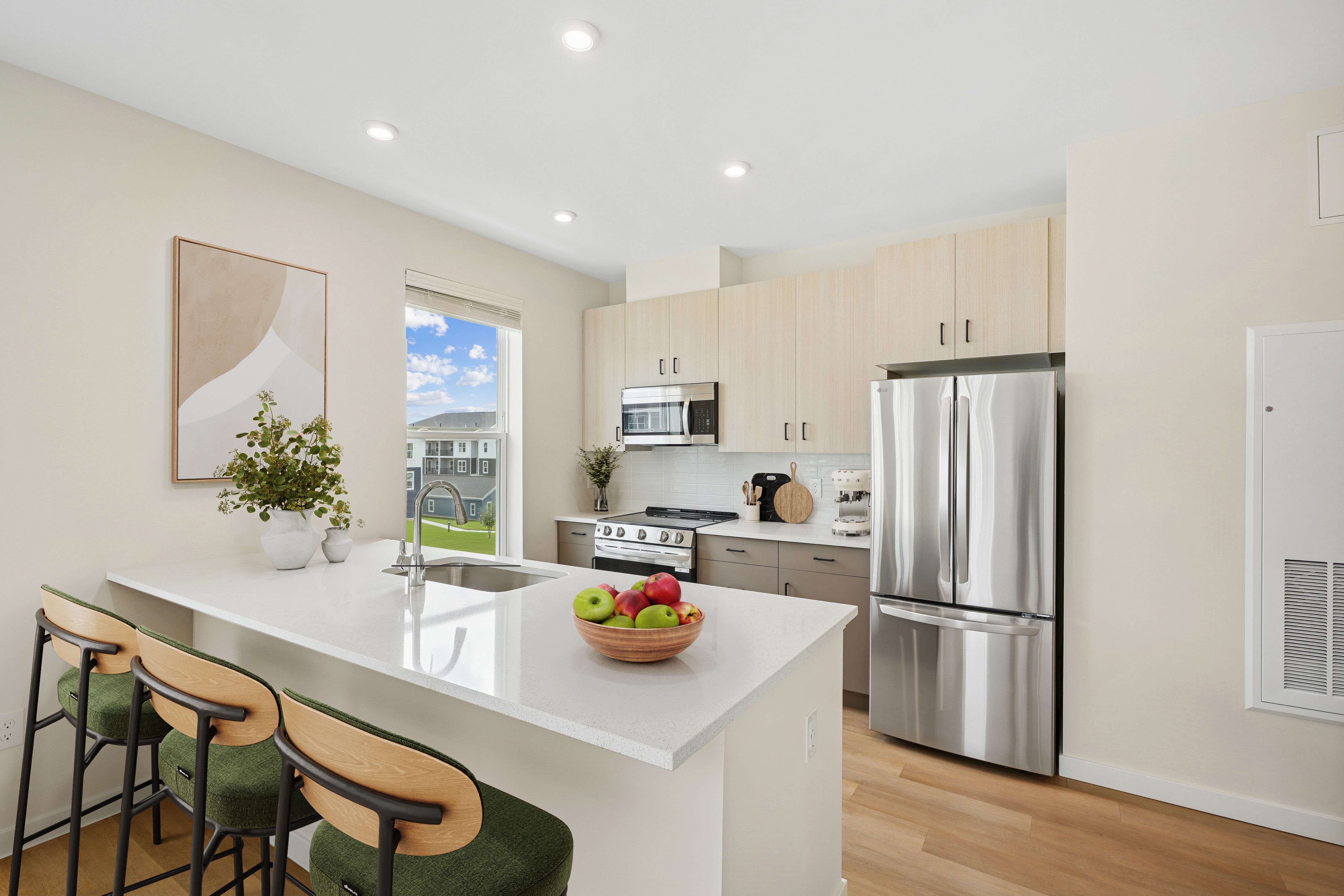 A kitchen with a white counter top and a stainless steel refrigerator.