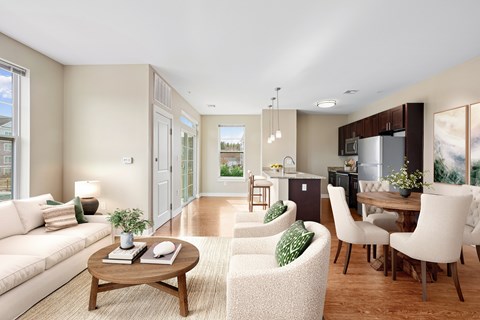 A modern living room with a white sofa, a wooden coffee table, and a kitchen area in the background.