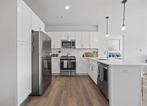 A modern kitchen with white cabinets and stainless steel appliances.