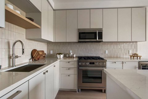 A modern kitchen with a stove top oven and a microwave above it.
