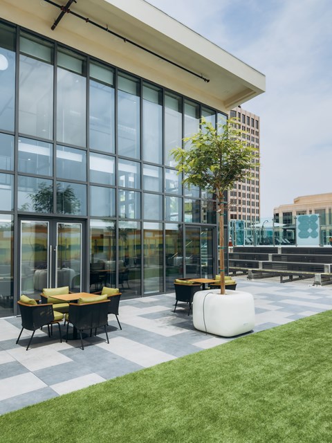 A modern building with a glass facade and a small outdoor seating area.