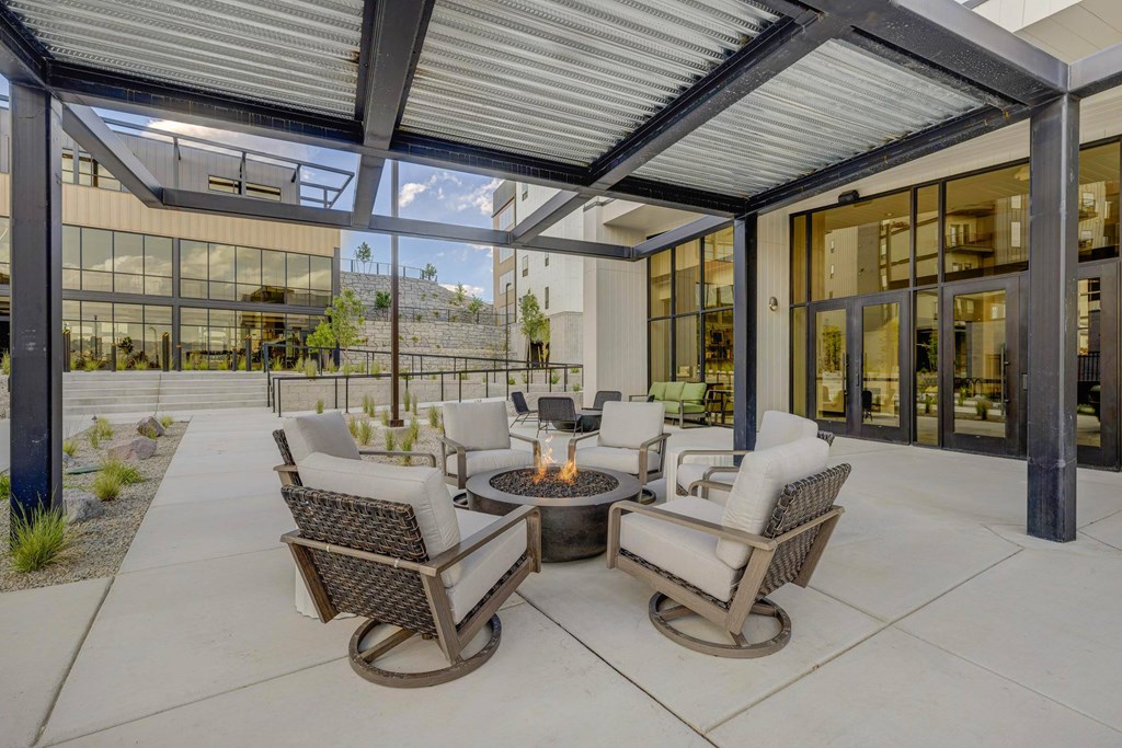 A patio with a fire pit and chairs.