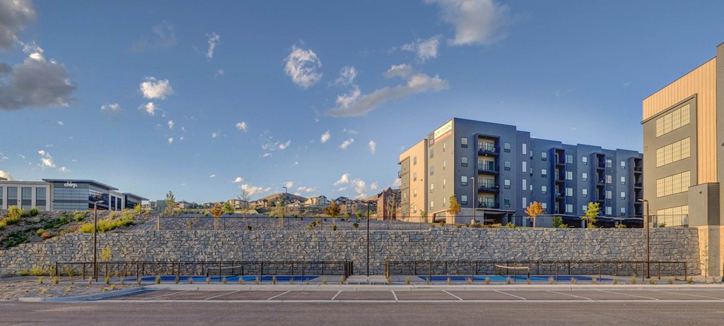 A large stone wall with a metal fence in front of a building.