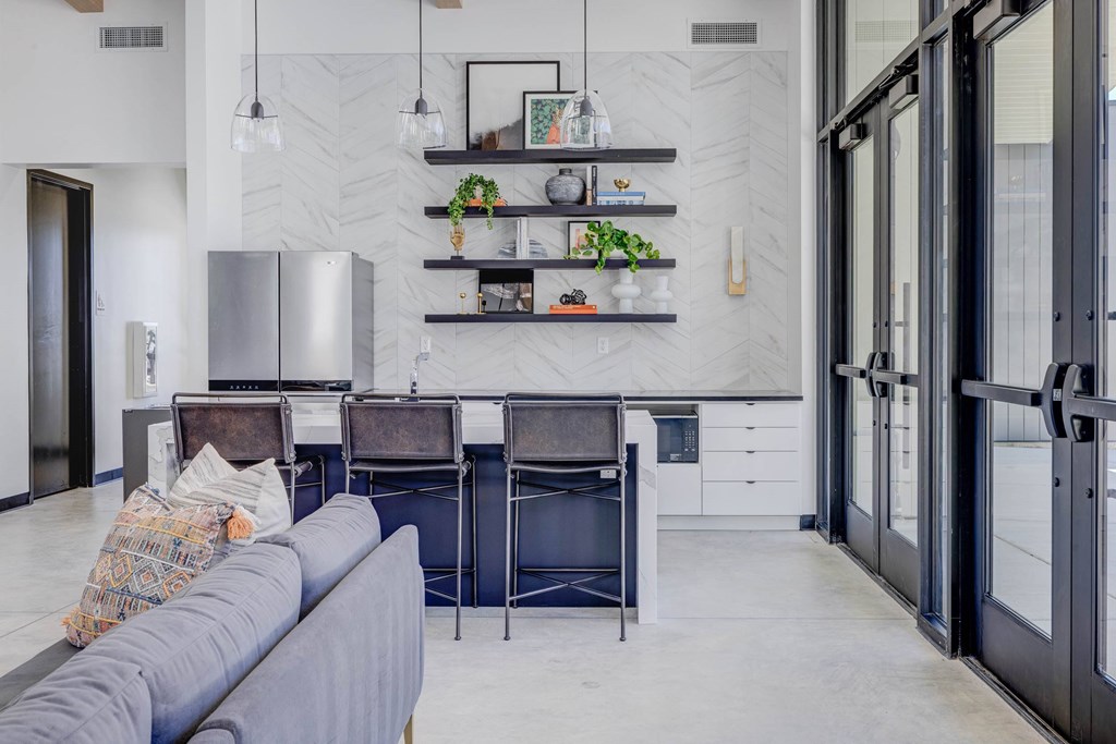 A modern kitchen with a grey couch and a marble backsplash.