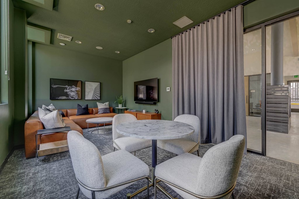 A living room with a grey sofa, a white table and a grey chair.