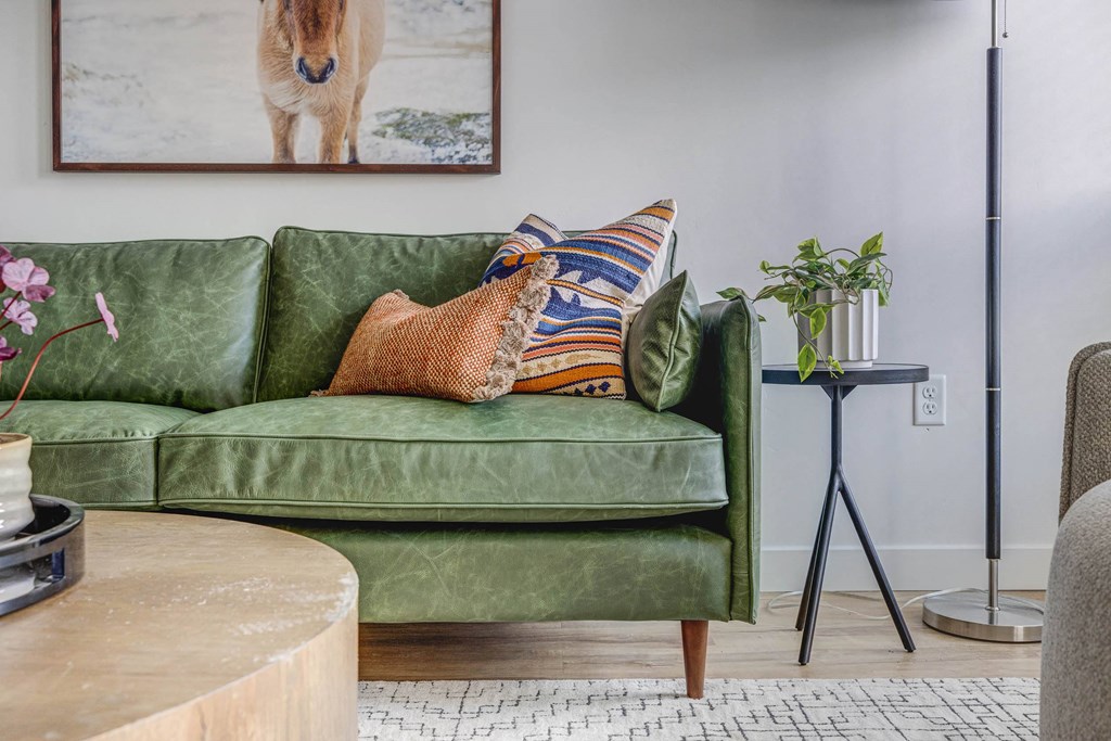 a living room with a green couch and a picture of a horse