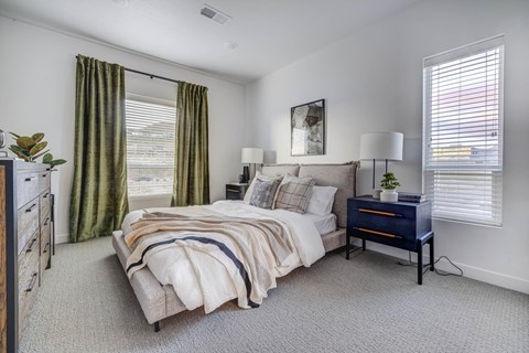 a bedroom with a bed and a dresser and windows