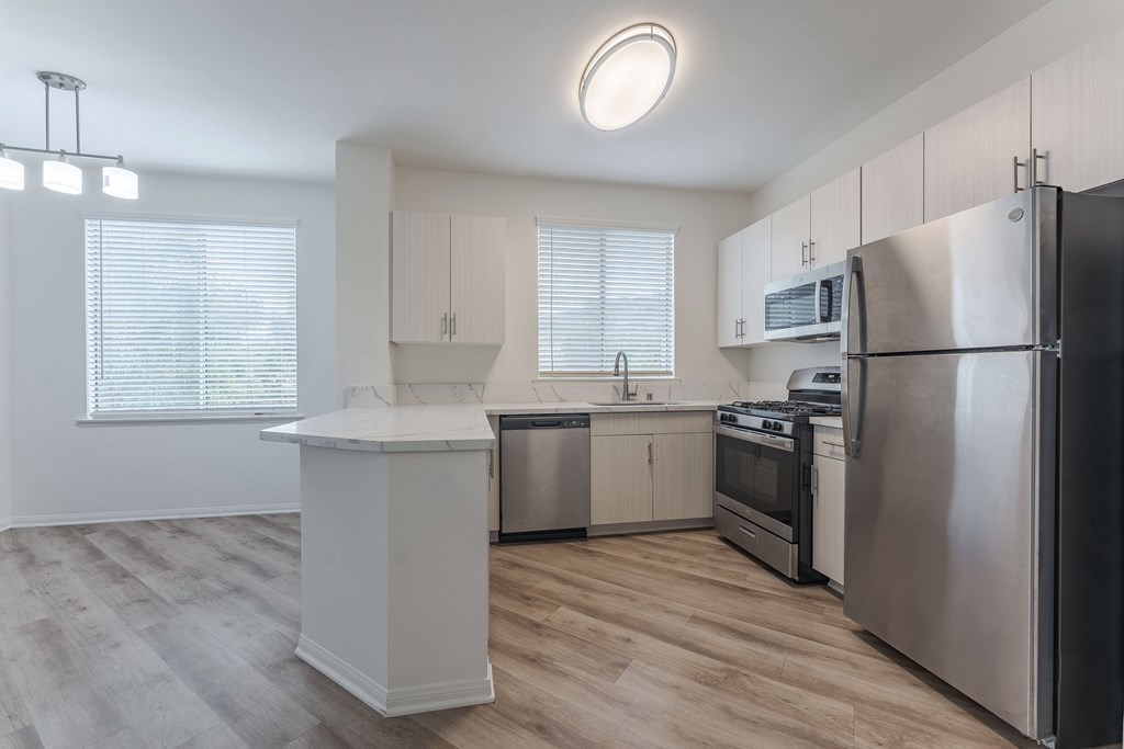 A modern kitchen with stainless steel appliances and wooden flooring.