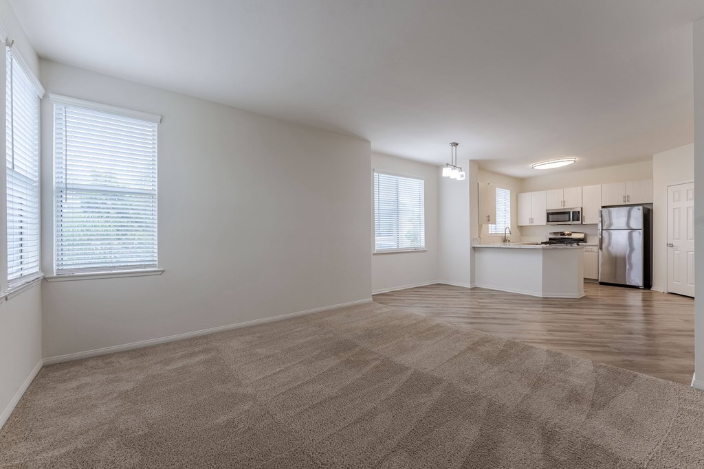 A spacious room with a kitchenette and a carpeted floor.