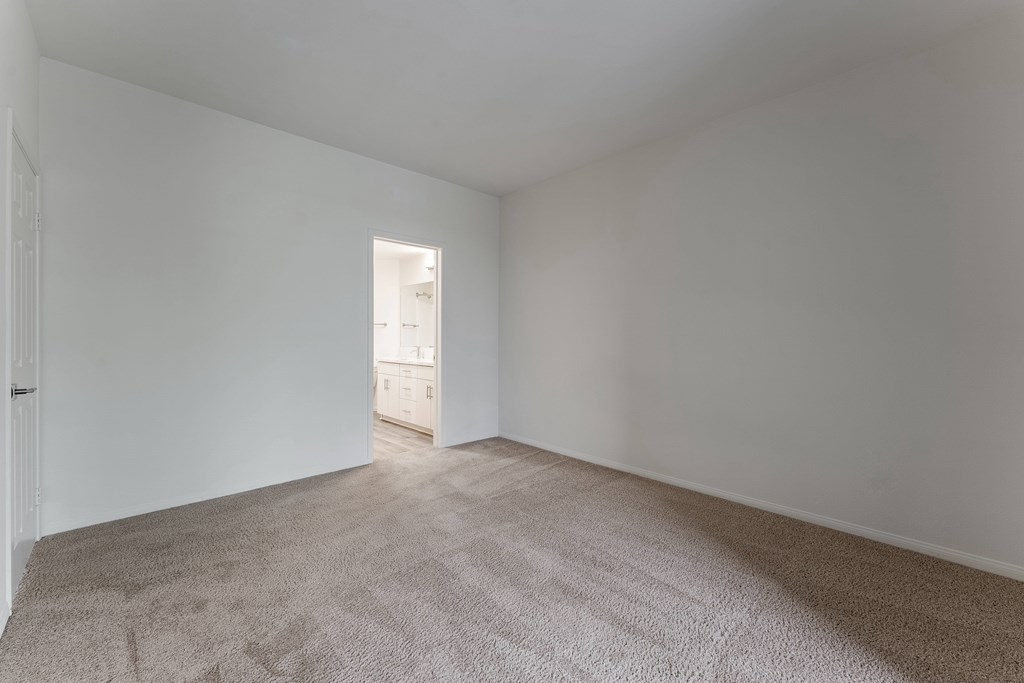 A room with a carpeted floor and a doorway leading to another room.
