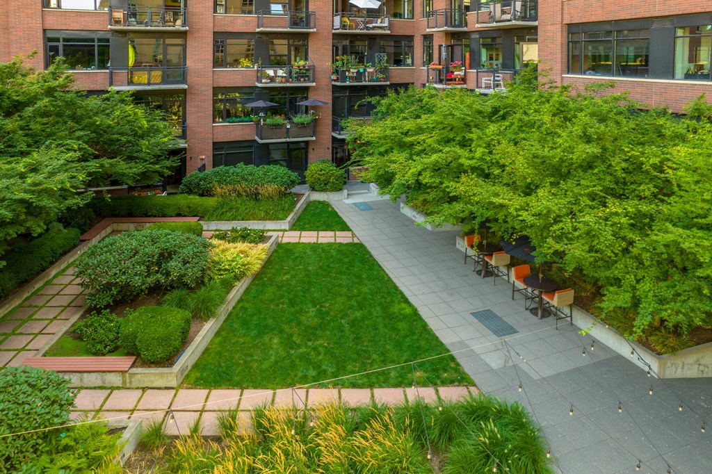 an aerial view of a courtyard with a grassy area and a brick building in the background
