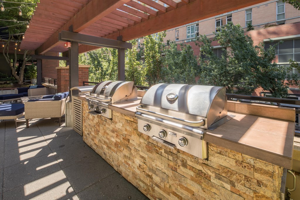 a brick wall with two bbq grills and a pergola