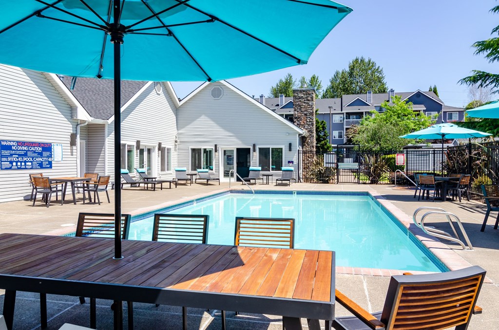 a resort style swimming pool with patio table and an umbrella at The Arden Apartments, Gresham Oregon