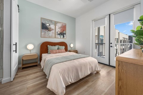 A bedroom with a bed, nightstand, and a painting on the wall.