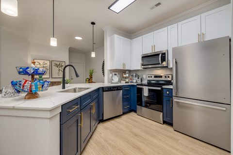 A modern kitchen with a stainless steel refrigerator and dark blue cabinets.