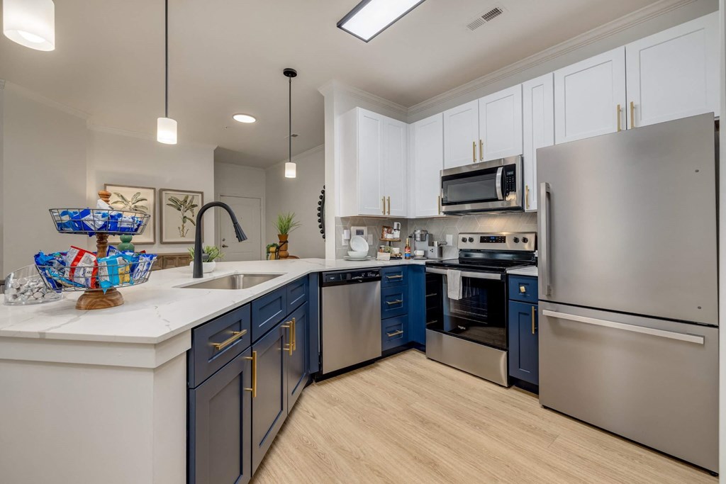 A modern kitchen with a stainless steel refrigerator and dark blue cabinets.