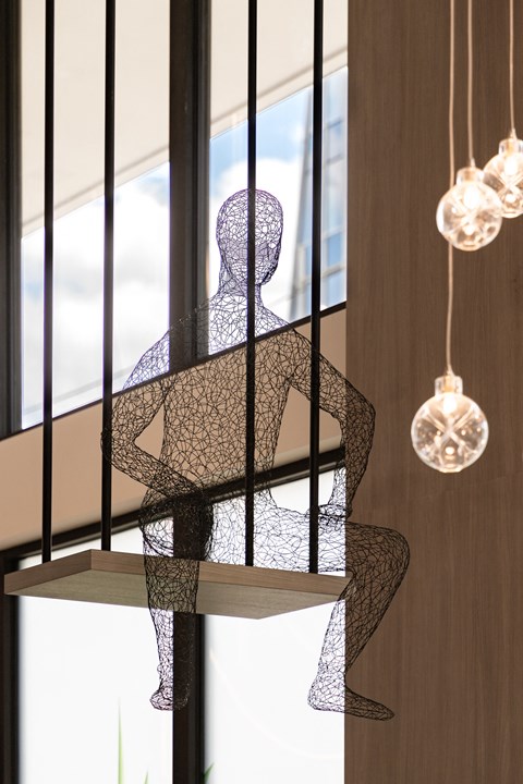 a sculpture of a person sitting on a shelf in front of a window