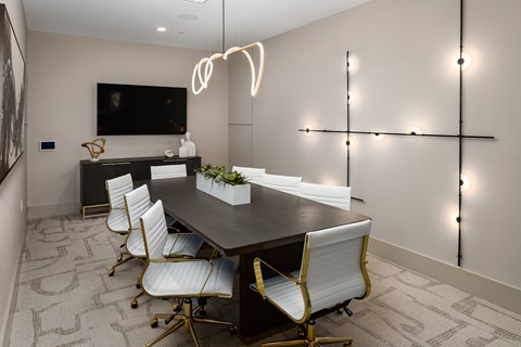a conference room with a black table and white chairs and a television