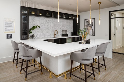a kitchen with a large white counter top and chairs