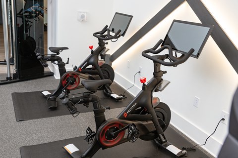 two exercise bikes in a gym with mirrors on the wall