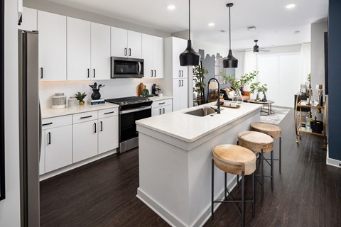 a kitchen with white cabinets and a large island with three stools