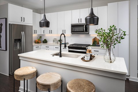 a kitchen with white cabinets and a white counter top with three stools