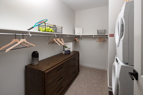 a walk in closet with a dresser and a refrigerator