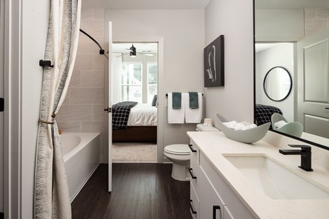 a bathroom with a shower toilet and sink and a bedroom with a bed