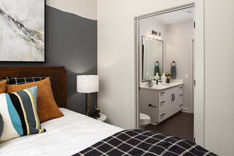 a bedroom with a bed and a bathroom with a sink and a mirror