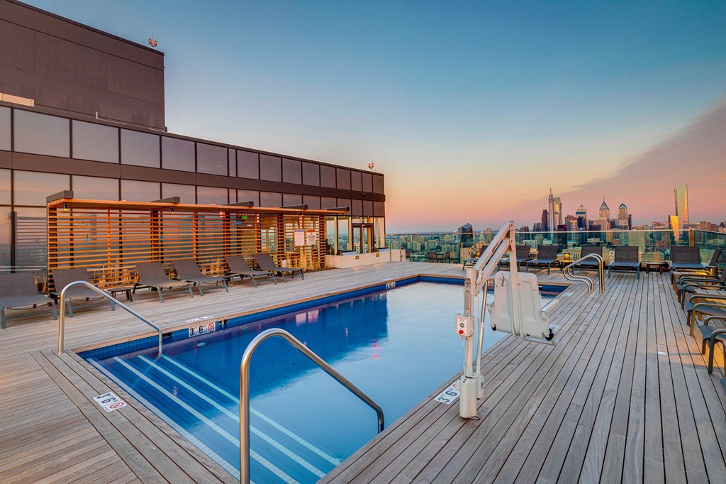 a swimming pool on the roof of a building with a city skyline in the background