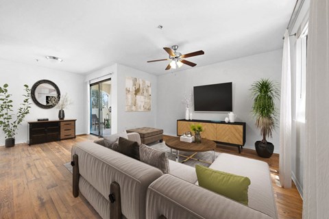 A living room with a grey couch and a wooden floor.