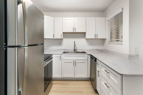 A kitchen with white cabinets and a stainless steel refrigerator.
