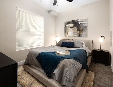 a bedroom with a bed and a large window with blinds