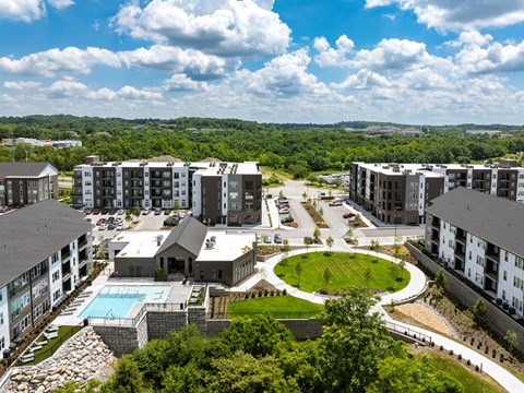 an aerial view of an apartment complex with a pool and green field