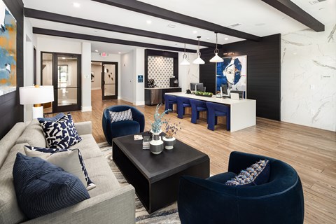 A modern living room with a grey sofa, a black coffee table, and a blue armchair.